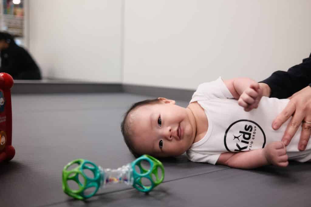 Education - Picture of a baby laying down wearing a kids physio group white onsie