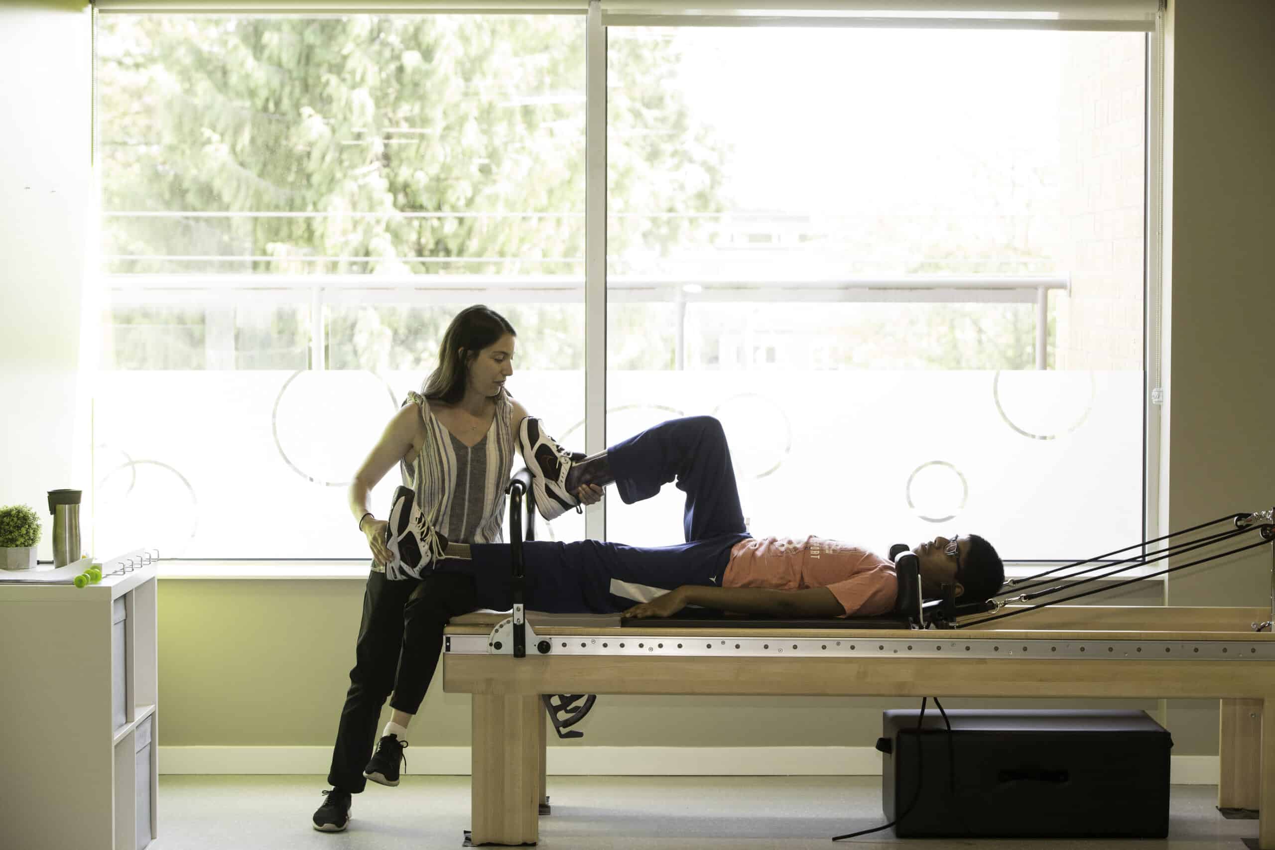 Education - Picture of a physiotherapist at a Kids Physio Group clinic performing an excise with a patient.